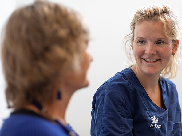 Eine Person in blauen Kitteln lächelt.