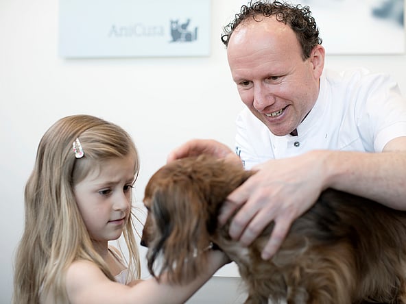 Eine Person und ein Kind, die einen Hund streicheln.