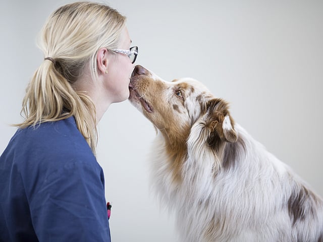 Eine Frau, die einen Hund küsst.