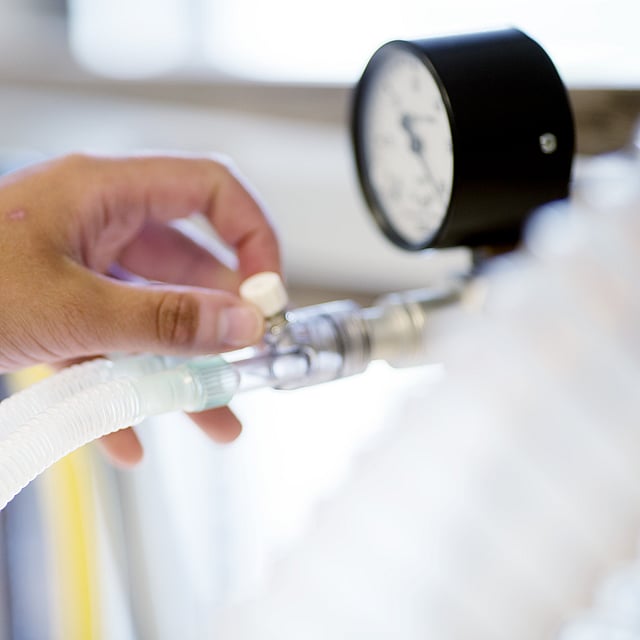 Eine Person, die einen Schlauch mit einem Manometer hält.