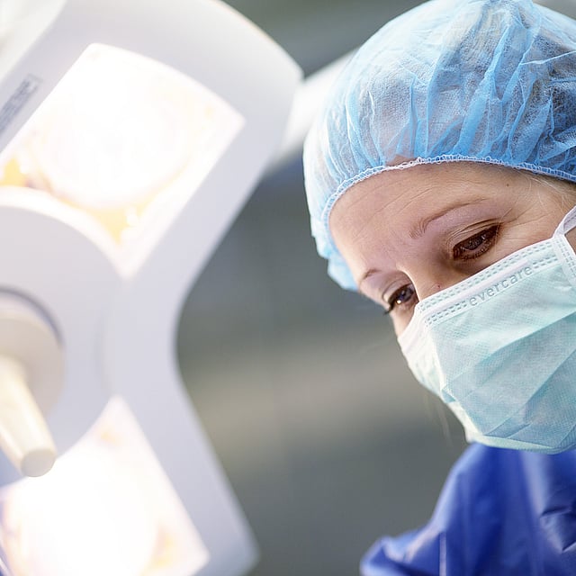 Eine Person, die eine OP-Kappe und eine Maske trägt.