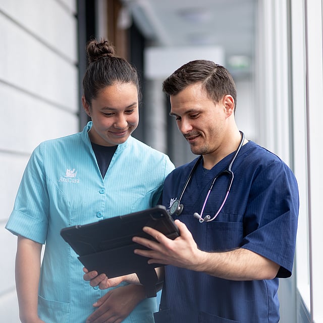 Eine Person und eine Person, die auf ein Tablet schaut.