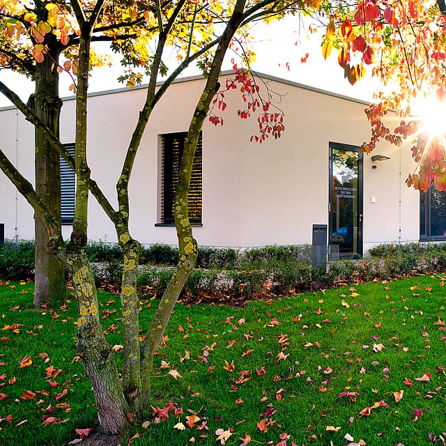 Ein Gebäude mit Bäumen und Gras davor.