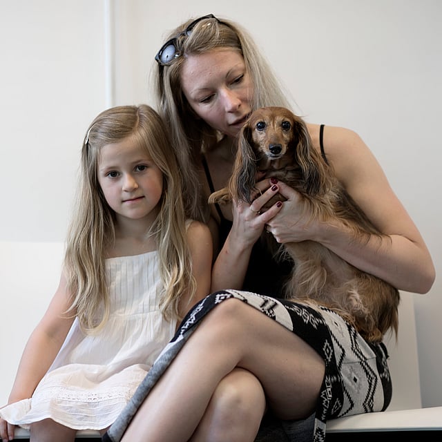 Eine Person und ein Kind, die einen Hund halten.