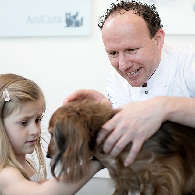 Eine Person und ein Kind, die einen Hund streicheln.