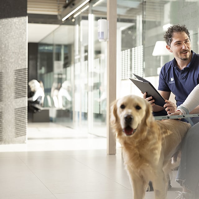 Eine Person und eine Person, die mit einem Hund auf einer Bank sitzt.