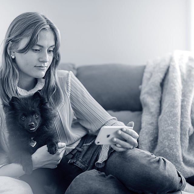 Eine Person, die auf einer Couch sitzt und einen Hund hält.