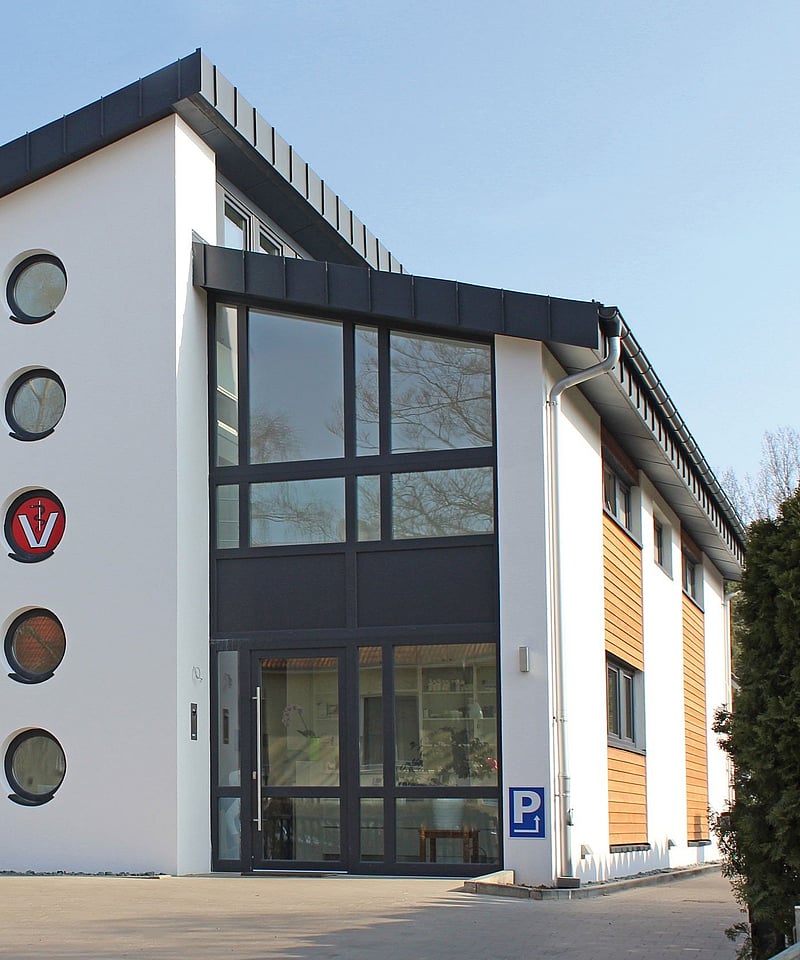 Das Haus, in dem sich die Praxis befindet, ist groß und modern. Der Eingang ist mit einer ganzen Glaswand ausgestattet.