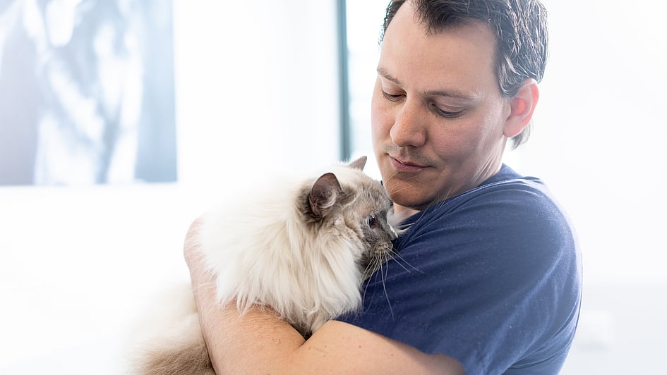 Eine Person, die eine Katze hält.