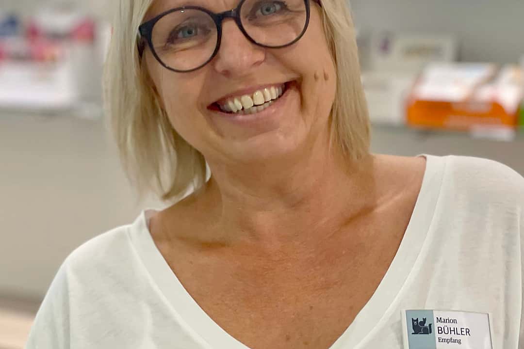 Nahaufnahme einer blonden Frau mit Brille, die lachend in die Kamera schaut.