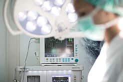 Ein Tierarzt führt gerade eine OP durch. Im Hintergrund steht ein Monitor, der den Herzrhythmus aufzeichnet.