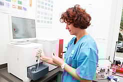 Eine Tierärztin füllt mit Hilfe einer Pipette eine Blutprobe in ein Untersuchungsgerät.