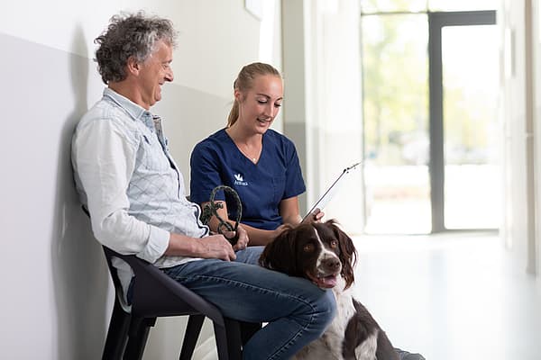 Eine Person und eine Person, die mit einem Hund auf einem Stuhl sitzt.