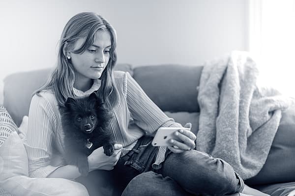 Eine Person, die auf einer Couch sitzt und einen Hund hält.