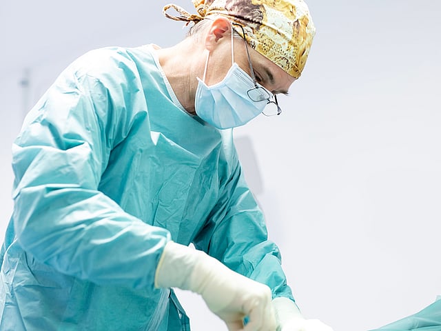 Ein Arzt mit OP-Ausrüstung und Maske.
