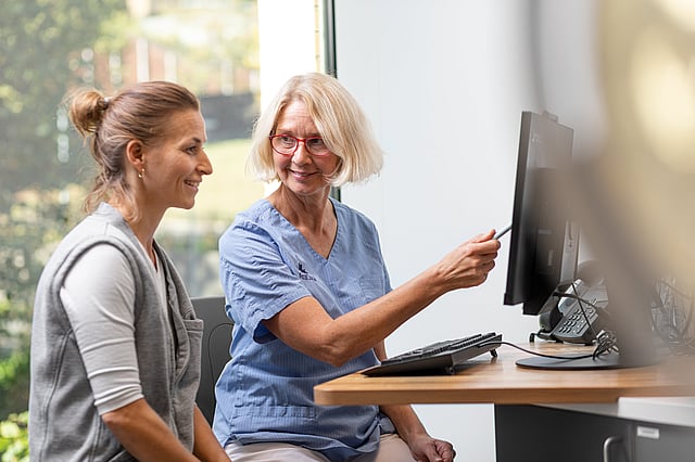 Eine Person, die auf einen Computerbildschirm zeigt.
