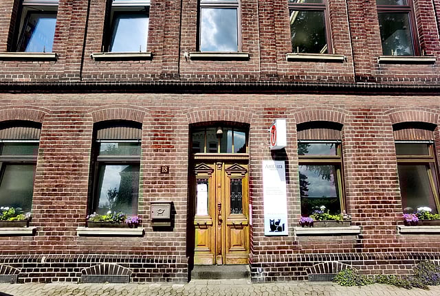 Ein Backsteingebäude mit einer Tür und Fenstern.