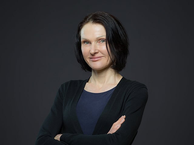 Eine Person mit schwarzen Haaren und verschränkten Armen.