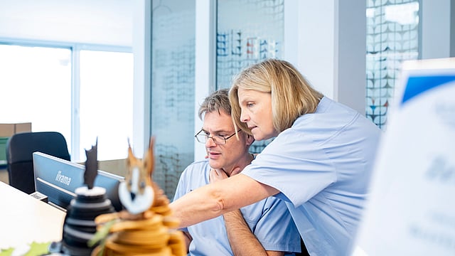 Eine Person und eine Person, die auf einen Computerbildschirm schaut.