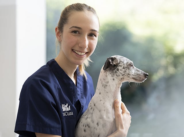 Tierärztin mit Hund im Arm lächelt in die Kamera